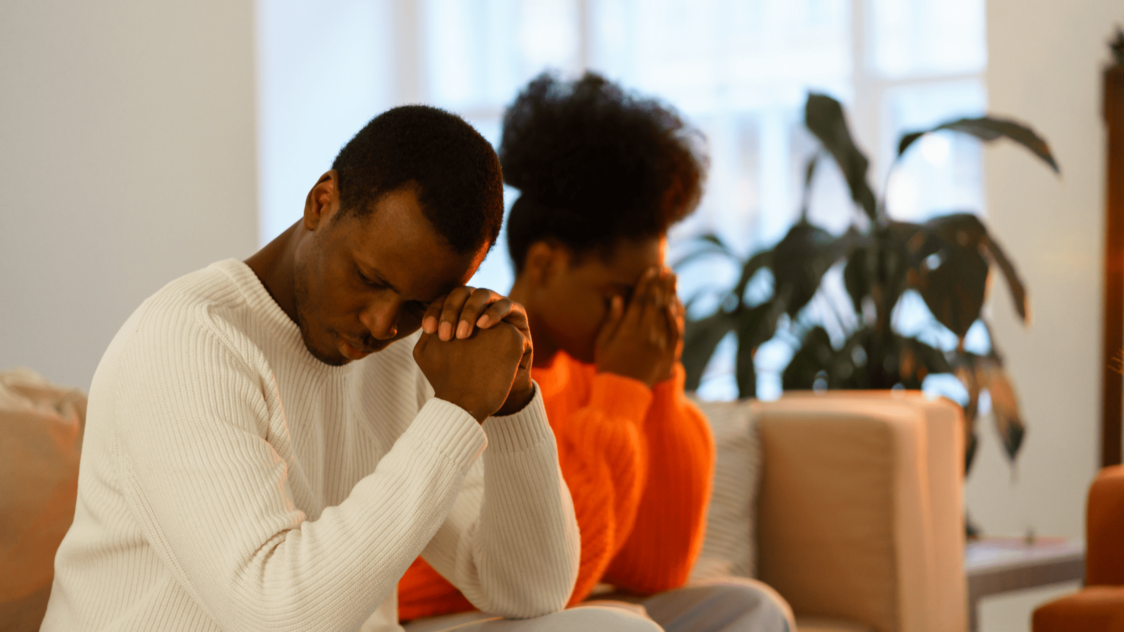 Sad black couple sitting on a sofa in their lounge