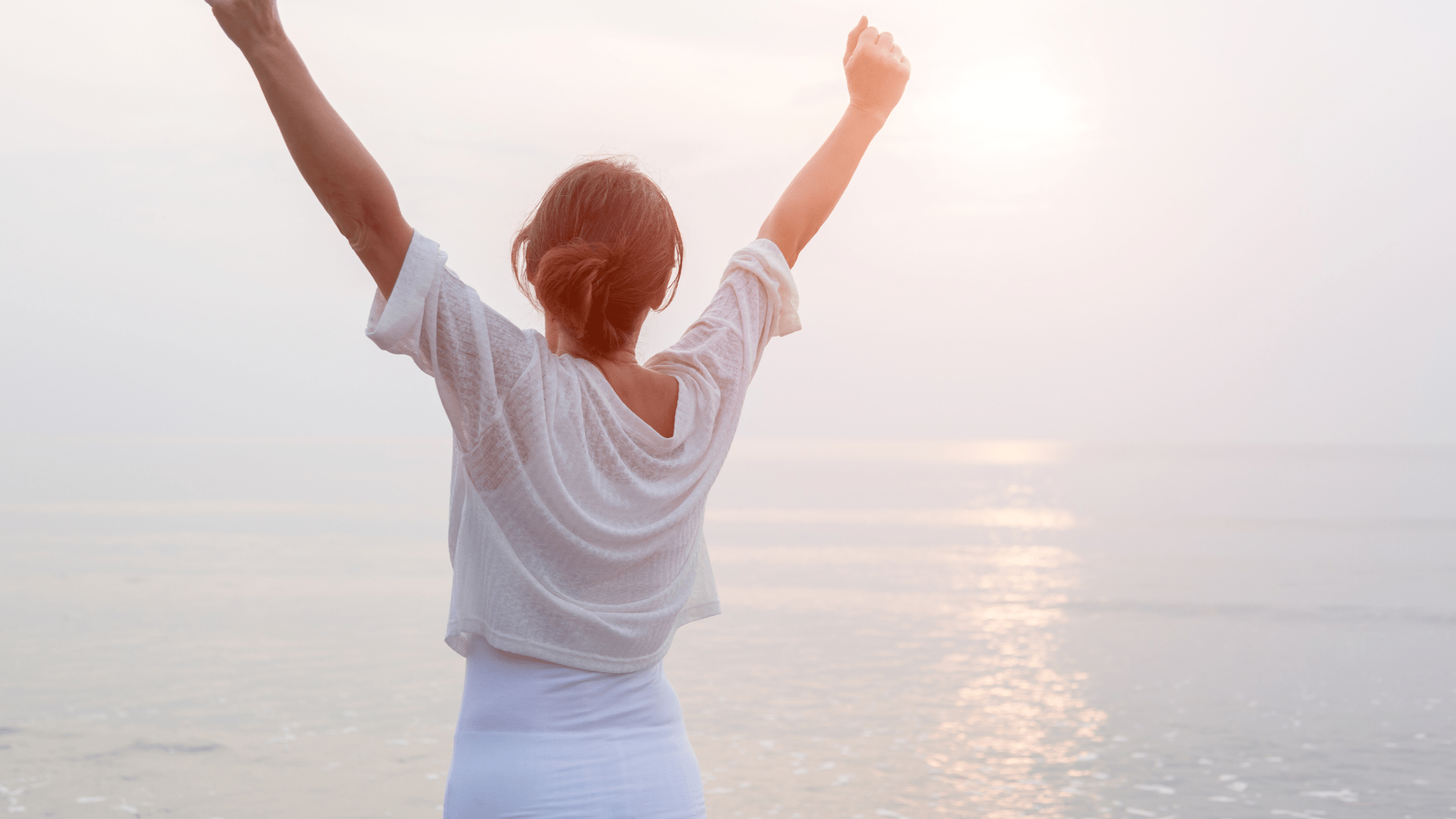 Woman embracing a sunset at the beach