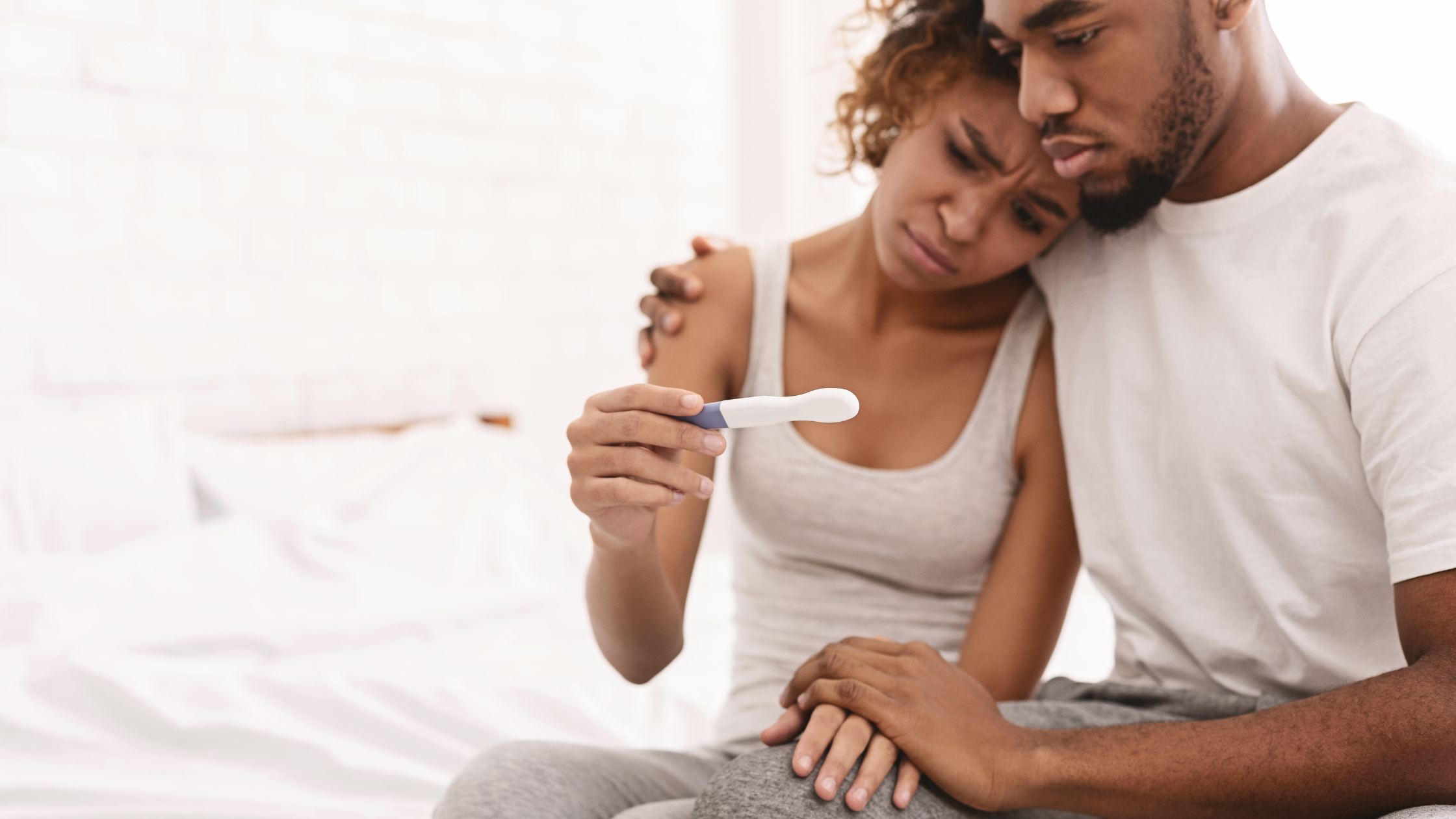Black couple sad looking at a negative pregnancy test