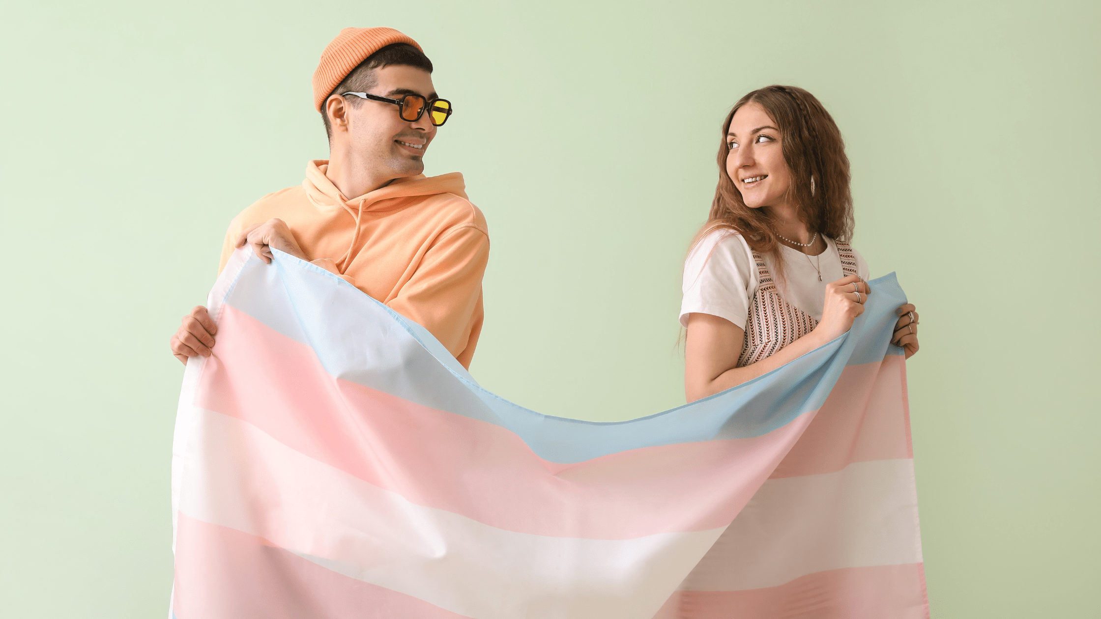 Two transgender people holding the transgender flag