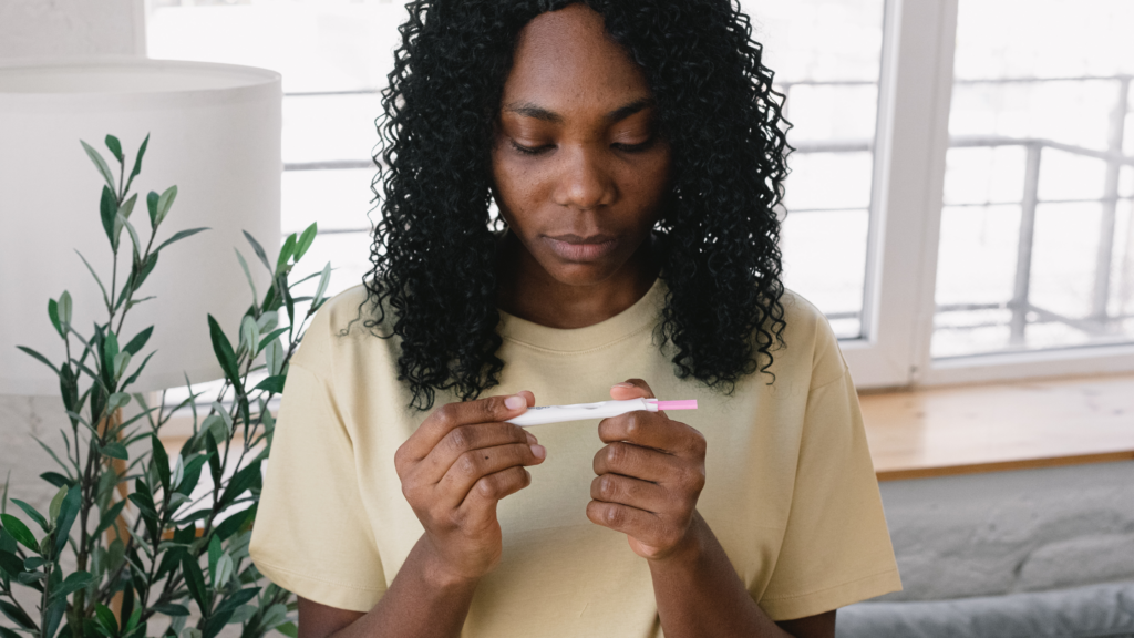 Black woman reading a pregnancy test