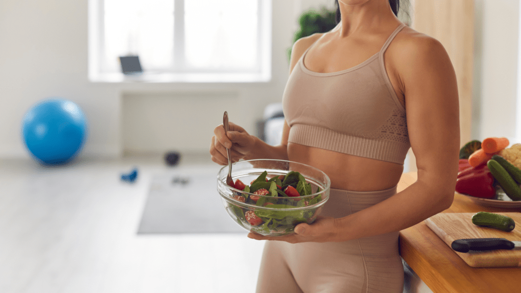 A healthy woman in workout clothes eating a salad