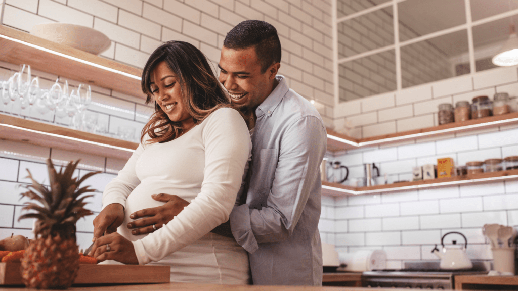 Pregnant couple chopping up fruit in their kitchen